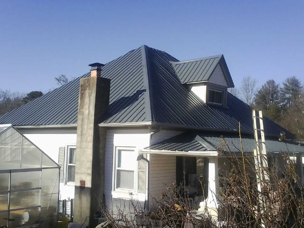 Dark blue standing seam metal roof on a white farmhouse with dormer — Slate & Tile Roof Repair by Roofing Brothers in Aaronsburg