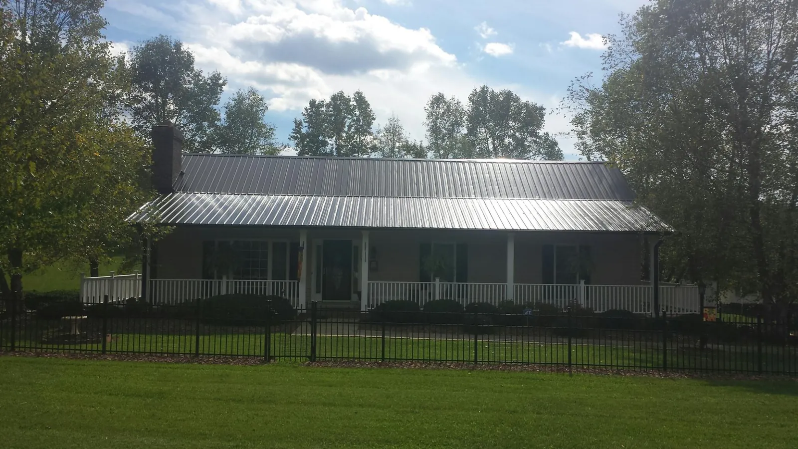 Gray metal roof on a brick ranch with a full width front porch — Gutter Guard Installation work by our crew in Aaronsburg
