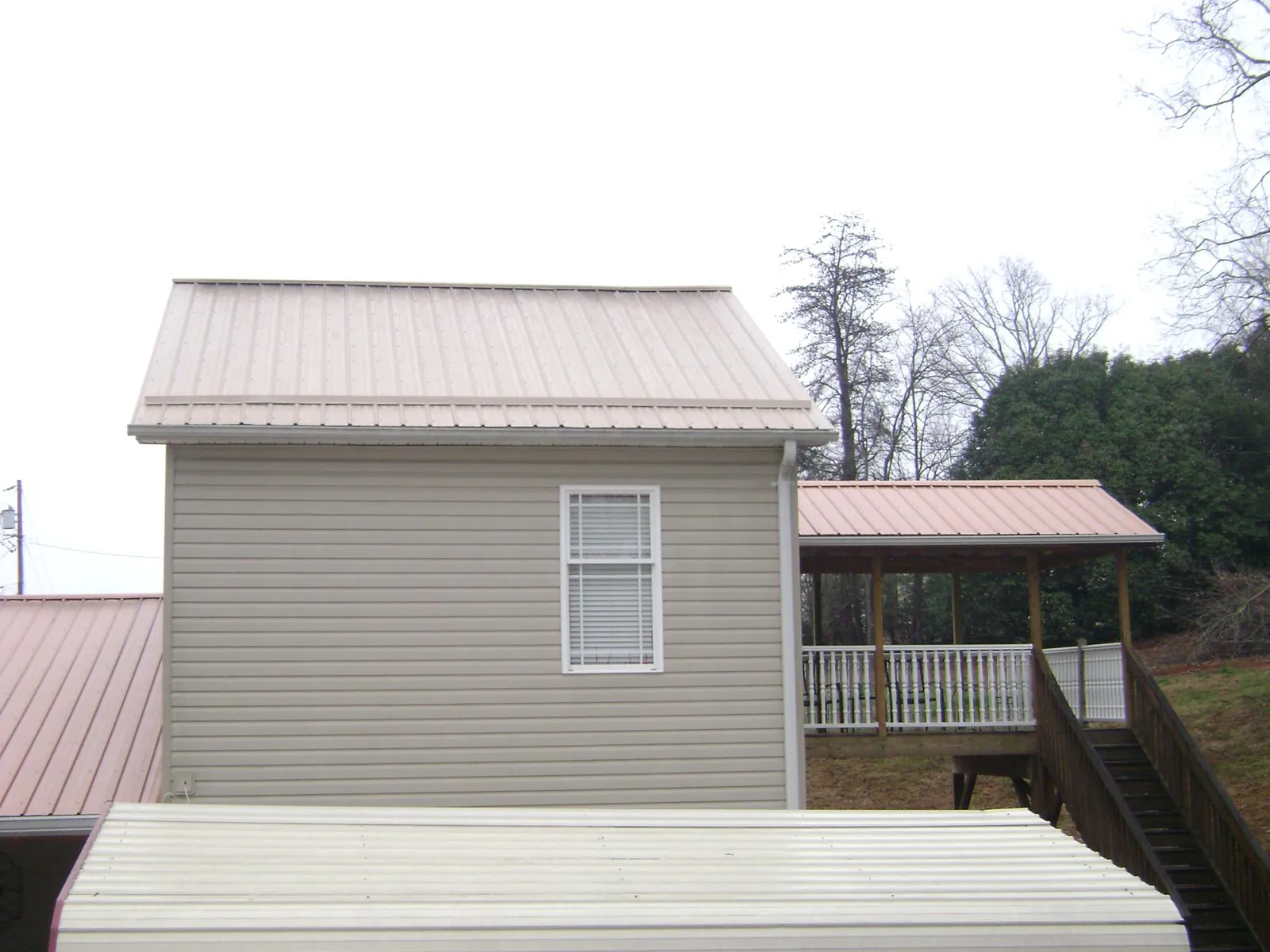 Tan metal roofs on a two story addition and attached porch, from a Roof Replacement job in Aaronsburg