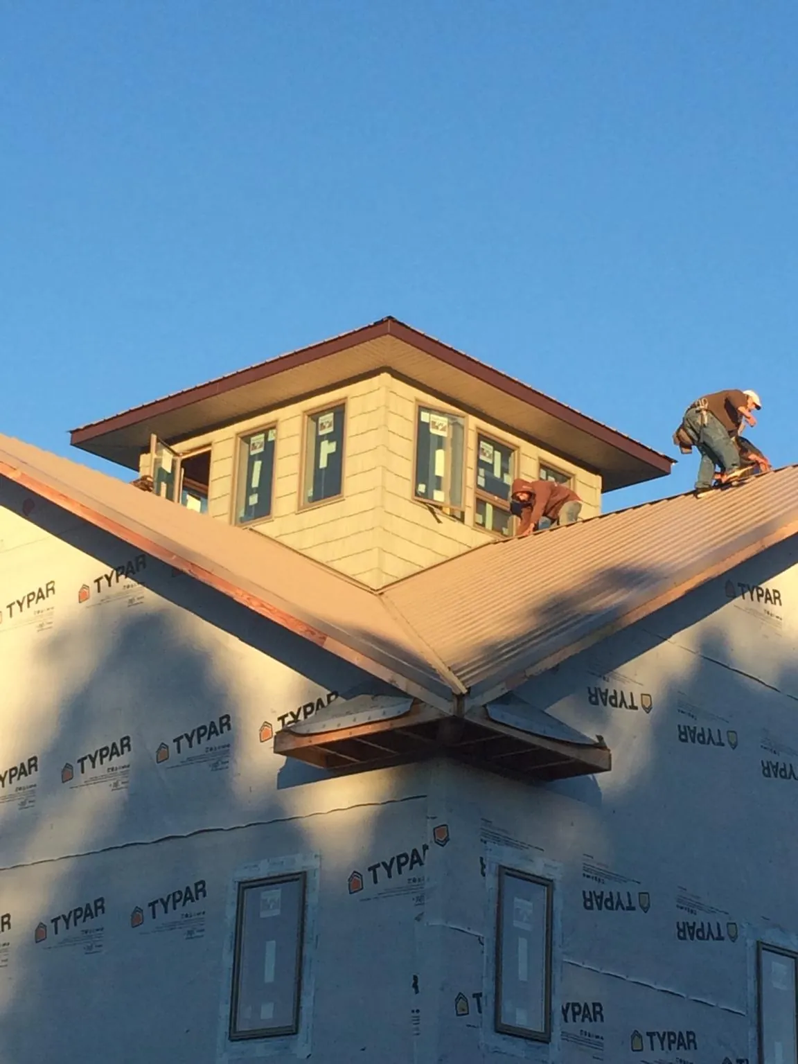 Roofers working around a rooftop cupola on a new metal roof at sunset — Roof Waterproofing in Aaronsburg by Roofing Brothers